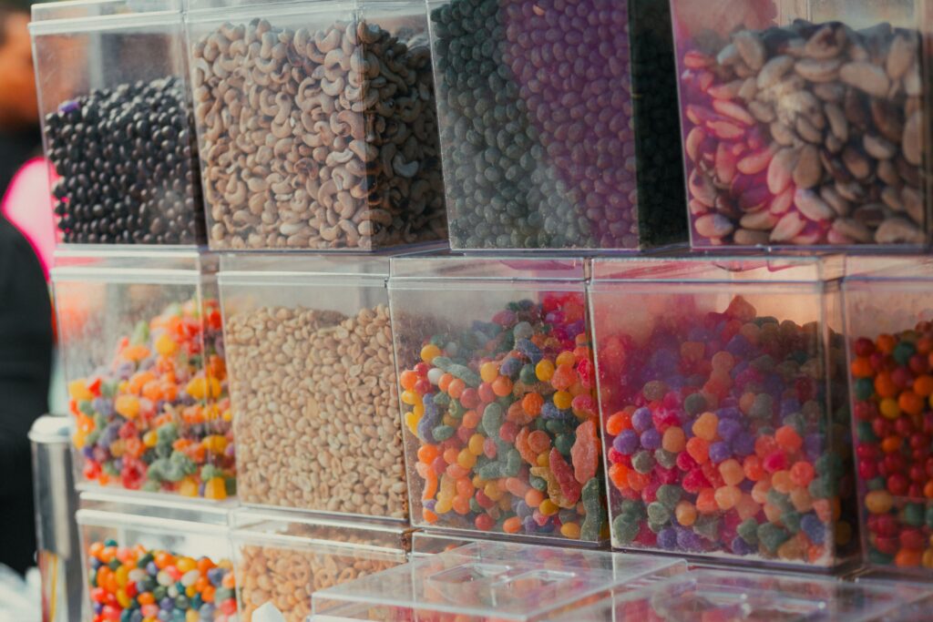 A vibrant display of assorted candies and nuts in clear containers at a market stall.