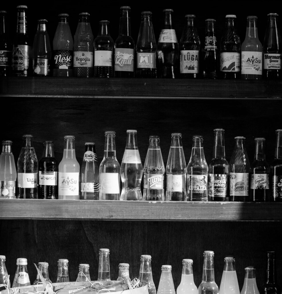 A black and white display of various bottled drinks on wooden shelves.